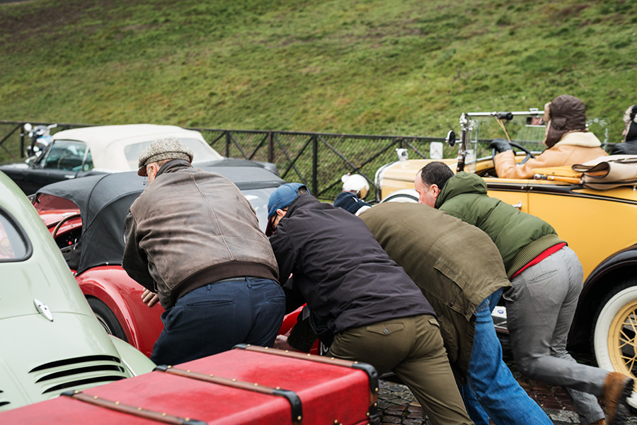 des hommes poussent une voiture ancienne